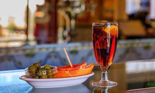 Traditional Spanish tapas of green olives and a jamon cured ham sandwich with a cocktail on a bar counter at a bar in Madrid, Spain